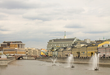 panoramic view of the Kadashevskaya embankment of the Drainage Canal with beautiful water fountains and historical architecture against the background of a cloudy sky in Moscow