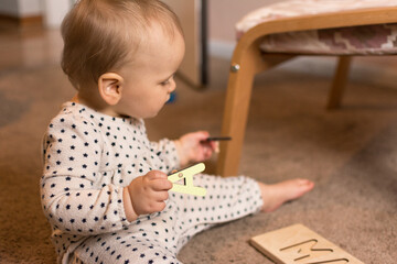 Ten month old toddler playing with a wooden letter puzzle on the floor