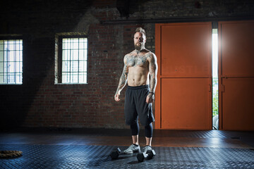 Shirtless male fitness coach standing at gym