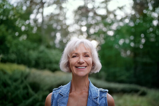 Portrait of happy elderly woman smiling and looking at camera outdoors.