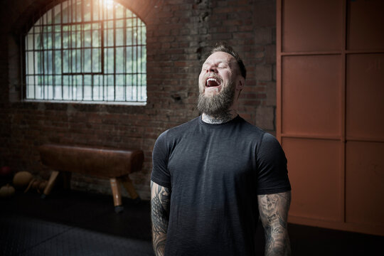 Male fitness coach laughing while standing in gym