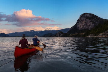 Adventurous people on a canoe are enjoying the beautiful Canadian Mountain Landscape. Blue Twilight...