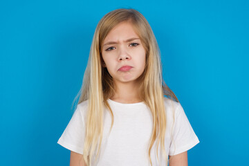 beautiful Caucasian little girl wearing white T-shirt over blue background depressed and worry for distress, crying angry and afraid. Sad expression.