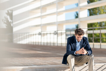 Businessman smiling while sitting on steps during sunny day
