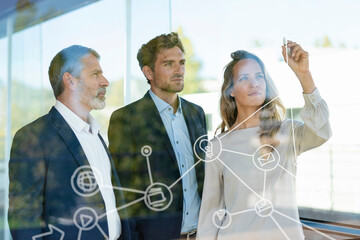 Businesswoman drawing flow chart while standing by colleague at office