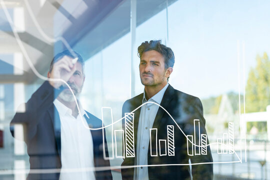 Mature businessman drawing graph while working with colleague at office