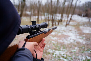 Young man aiming at target with the hunting rifle.