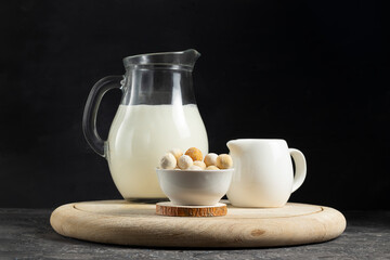 Central asian traditional kurut cheese in a white plate with a creamer and a jug of milk on a wooden board
