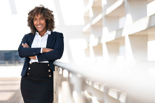 Confident Female Professional Smiling While Standing With Arms Crossed At Office Terrace