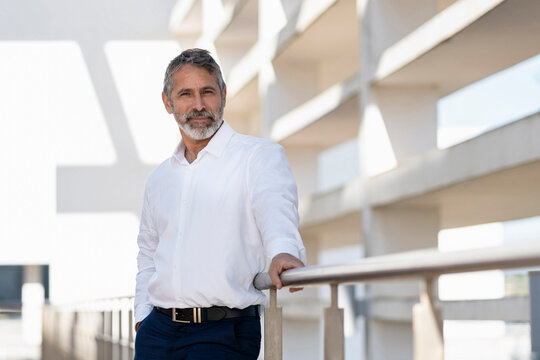 Male Professional Smiling While Standing By Railing At Office Terrace