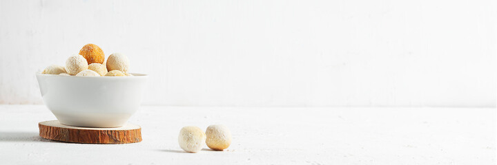 Central asian traditional cheese kurut in a white plate on wooden coasters on a light background
