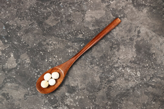 Traditional asian dry smoked kurut cheese in a wooden eco friendly spoon on a dark background copy