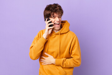 young man holding a cell laughing out loud at some hilarious joke