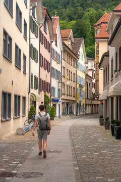 Explorer with backpack walking on Storchengasse street in old town of Chur, Switzerland