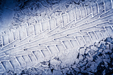 Fototapeta premium Diagonal traces of car tires in the snow on the asphalt. Close up view from above