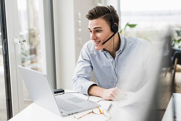 Young male professional attending video call through laptop sitting at desk