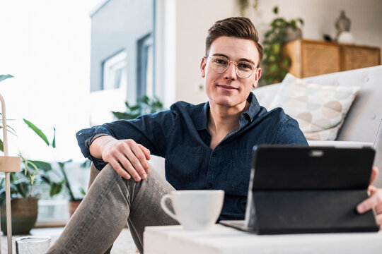 Smiling Young Man In Eyeglasses With Laptop Sitting In Living Room