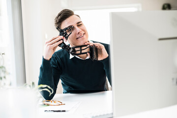 Smiling young male engineer with robotic arm at home office