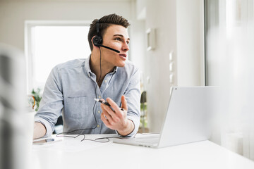 Male entrepreneur discussing on video call through laptop during meeting at home office