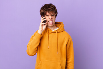 young man holding a cell feeling disgusted and irritated and tongue out