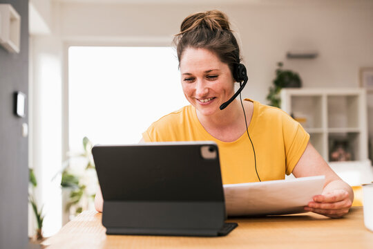 Smiling businesswoman wearing headphones video conferencing at home