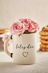 rosas rosadas en una taza que dice feliz dia por concepto del dia de las madres