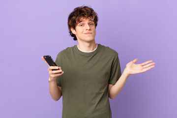 young man holding a cell feeling puzzled and confused and doubting