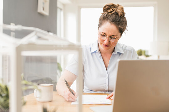 Businesswoman sitting at desk writing on document