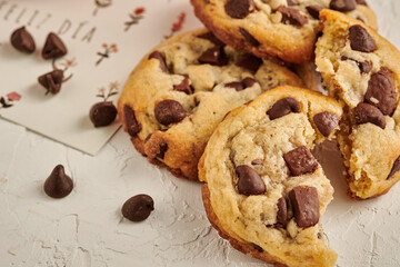 galletas de chocolate con chips  en una mesa blanca rustica con una tarjeta que dice feliz dia