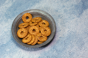 Sesame cookies in metal plate on blue background
