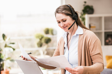 Smiling female entrepreneur examining document at home