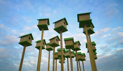 Yellow-green birdhouses standing against a blue sky with clouds