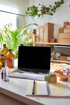 Laptop, note pad, soaps, oils on table at workshop