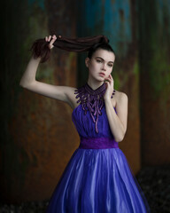 Portrait of a girl in a lilac dress between the piles of the pier