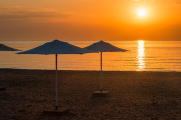 Row of beach umbrellas on a sandy beach by the sea in the morning