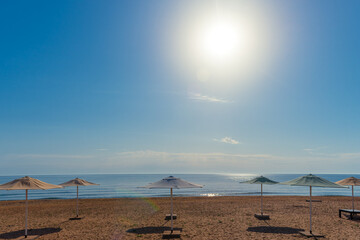Row of beach umbrellas on a sandy beach by the sea in the morning