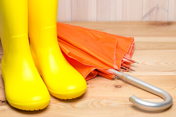 A pair of yellow rain boots and  orange umbrella
