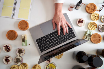 Female entrepreneur's hand typing on laptop over table