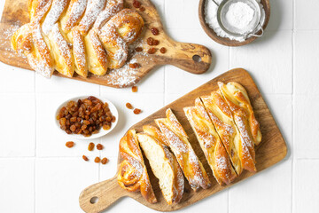 Sweet bun with cottage cheese and raisins on a serving board on a white kitchen table top view. The concept of home-made high-calorie pastries