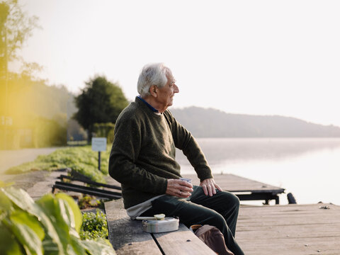 Senior man looking at view while sitting on bench - Powered by Adobe