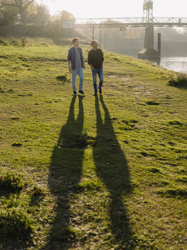 Son and father walking together on grass during autumn
