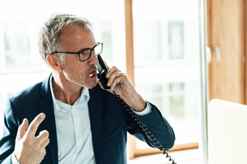 Worried businessman talking on telephone in office