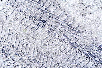 Multiple traces of car tires in the snow on the asphalt. Close up view from above