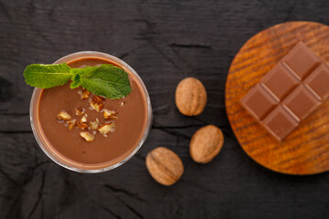 Chocolate cocktail with mint nuts in a glass near chocolate and nuts on a black background top view.