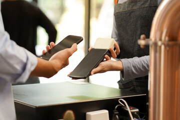 Close up owner and customer hands use smartphone to pay and transaction cashless no touch by NFC...