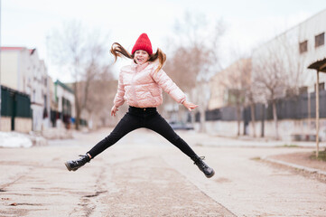 Laughing girl jumping on road against sky