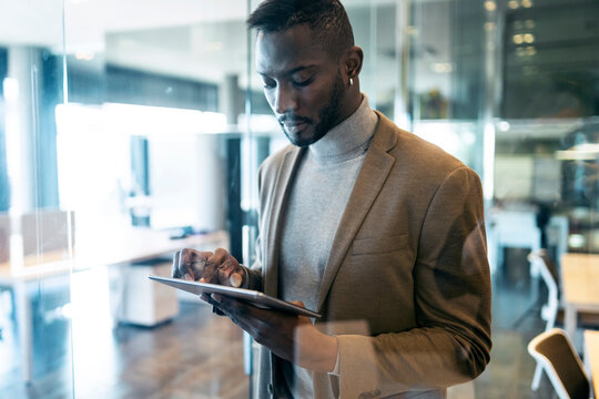 Entrepreneur using digital tablet while standing in office