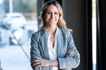 Confident businesswoman smiling while standing at office