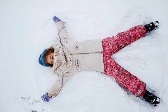 Playful girl making snow angel during winter