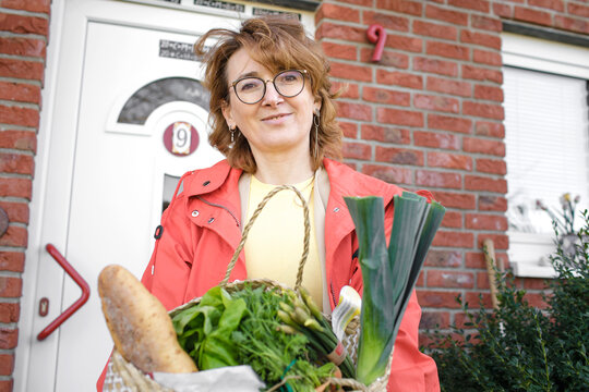 Redhead woman with groceries standing against door